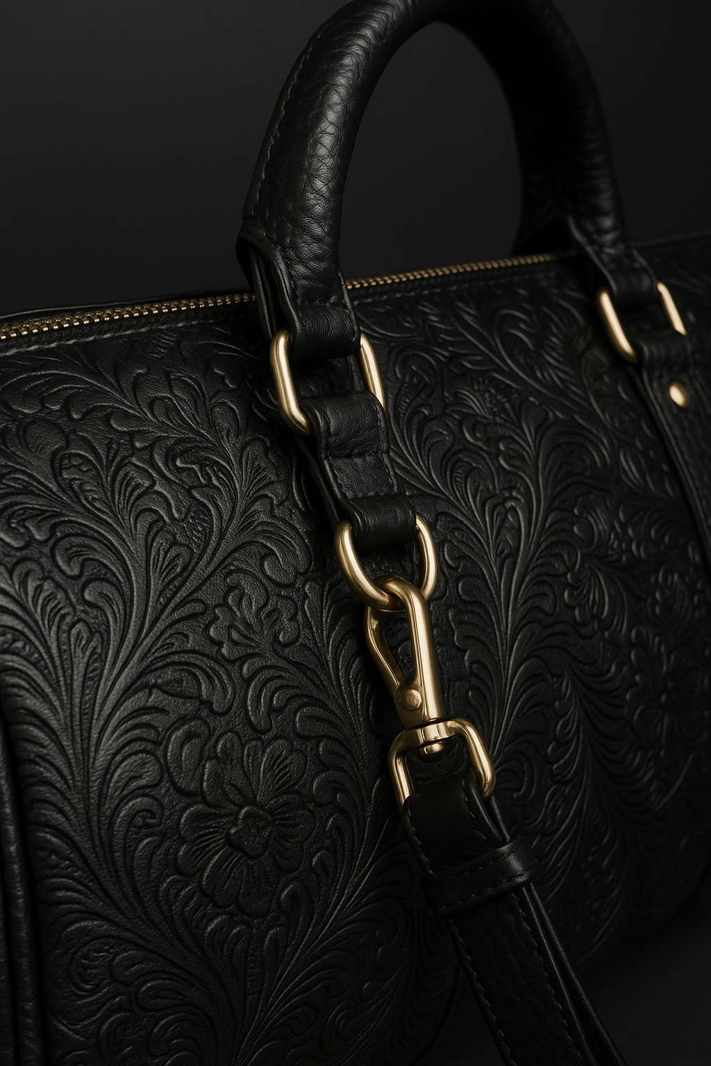 Close-up of embossed black leather duffel bag with floral detailing and gold hardware